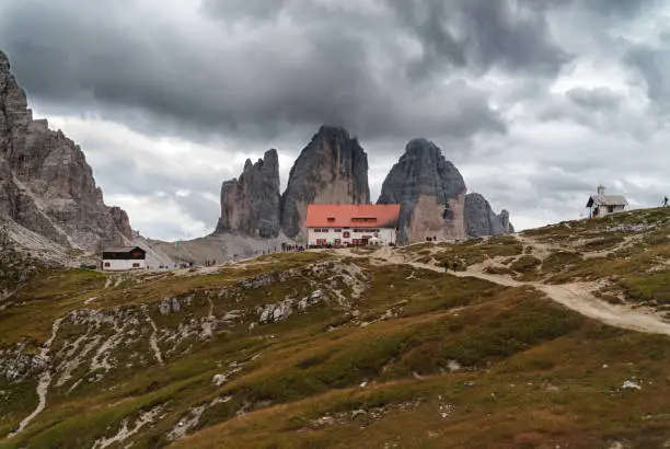 Dreizinnenhütte and chapel in front of Monte Paterno and cloud-covered Drei Zinnen, Dolomites, Italy