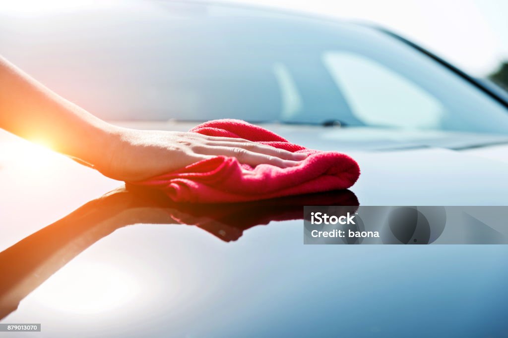 Main de femme séchage le capot du véhicule avec une serviette rouge - Photo de Voiture libre de droits