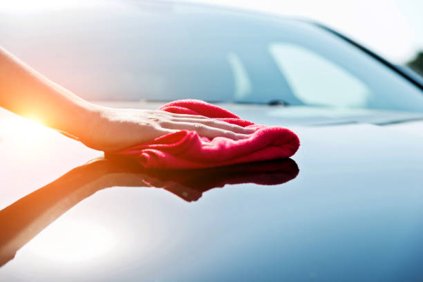 donna che asciuga a mano il cofano del veicolo con un asciugamano rosso - car wash car cleaning washing foto e immagini stock