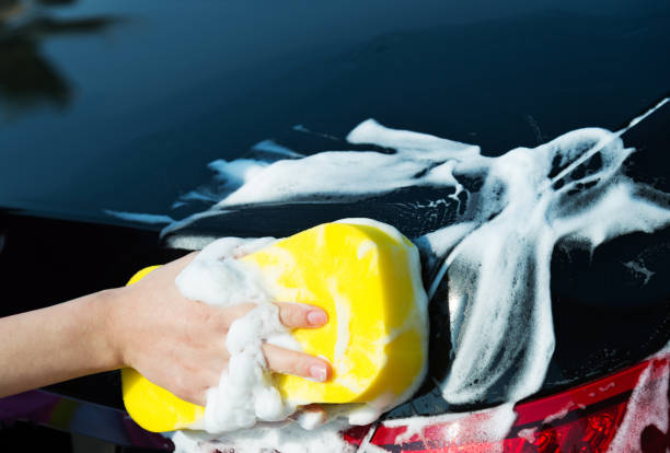 istock Woman hand cleaning the headlight with a bath sponge 879015626
