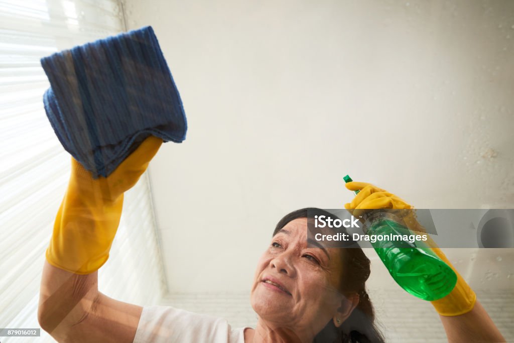 Wiping off every spot Woman spraying detergent on glass table, view from below Housekeeping Staff Stock Photo