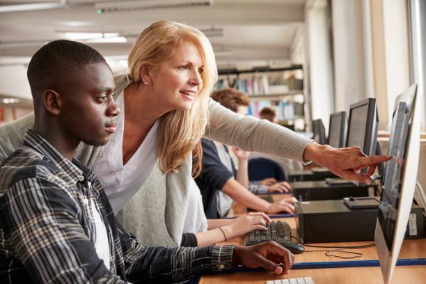 istock Teacher With Male Student Working On Computer In College Library 879041592