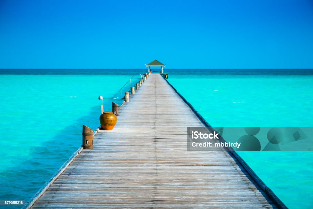 Jetty at Dhiffushi Holiday island, South Ari atoll, Maldives Jetty at tropical paradise beach at Dhiffushi Holiday island at South Ari atoll, Maldives. Beautiful turquoise Indian ocean sea with white sand. Luxury travel holidays background. Property released. Beach Stock Photo