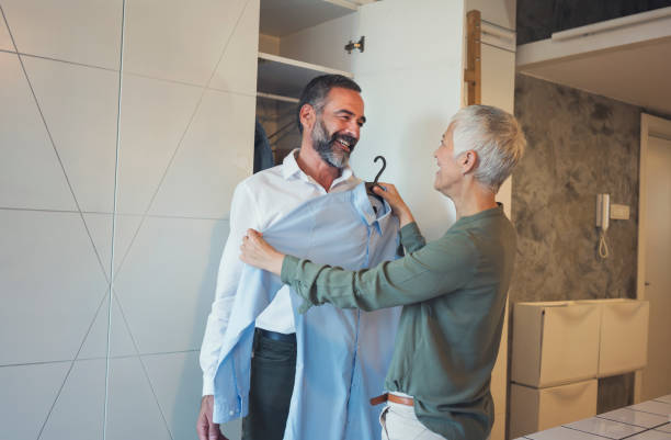 Preparing for work Beautiful mature couple at home preparing for work, choosing shirt senior white shirt stock pictures, royalty-free photos & images