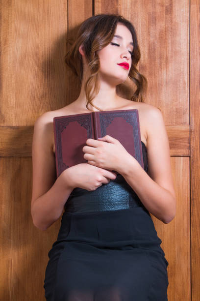 istock Young girl holding book, eyes closed 879069648