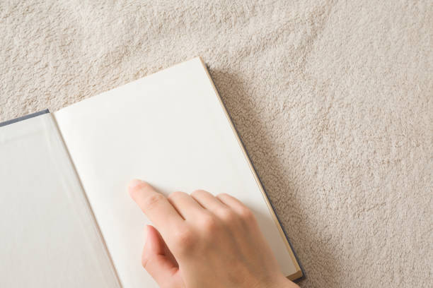 A cropped view of a woman holding a blank notepad against a natural green background.