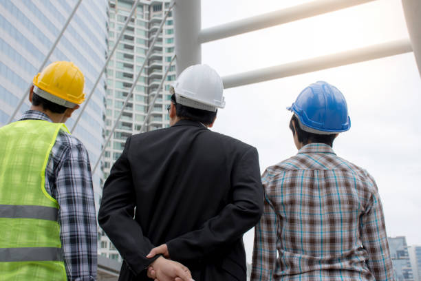 istock View from the back Asian engineering team wearing safety helmet and talking about construction project 879093684