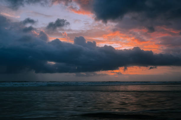 istock Dramatic golden sunset clouds reflected on the water sea. Tropical beach landscape at dusk 879108730