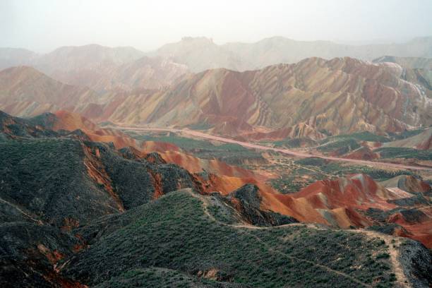 Seven Colour Mountain at Danxia landform geological park, Zhangye, Gansu, China Colourful rocks at the fourth viewing platform looking Qicai Shan (seven colour Mountain). Danxia landform geological park, near the town of Zhangye. Known for its colorful rock formations, has unusual colours of the rocks, which are smooth, sharp and in layers. They are the result of deposits of sandstone and other minerals that occurred over 24 million years. Gansu province, China zhangye danxia geopark china stock pictures, royalty-free photos & images