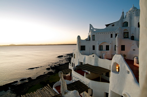 Casapueblo was built by the Uruguayan artist Carlos Páez Vilaró in Punta Del Este as his summer house and workshop. It is painted in white, and it is a perfect place to watch the sunset, listening to his poem as it is read. Nowadays it houses a museum, an art gallery, a hotel, and a cafeteria, which is always crowded during the sunset. The garden with its landscaping, looks like a fun maze with the arches.