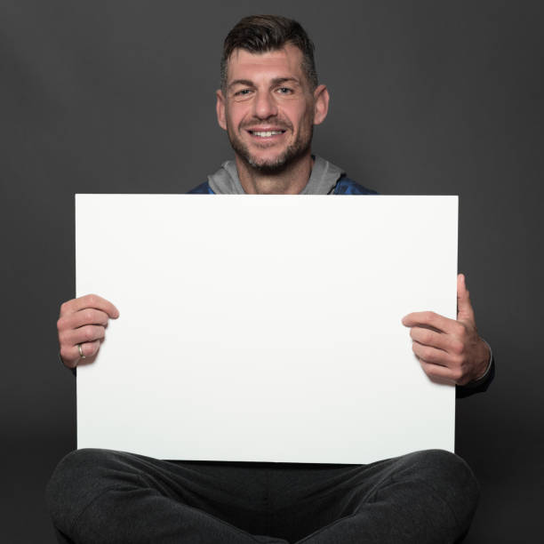 istock Athlete sits and holds a blank copyspace card 879137024