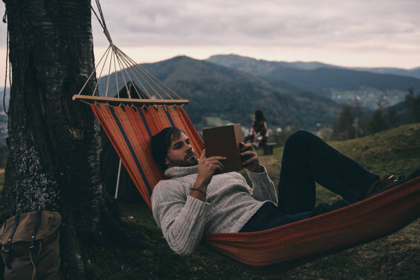 lascia indietro tutte le tue preoccupazioni. - men reading outdoors book foto e immagini stock