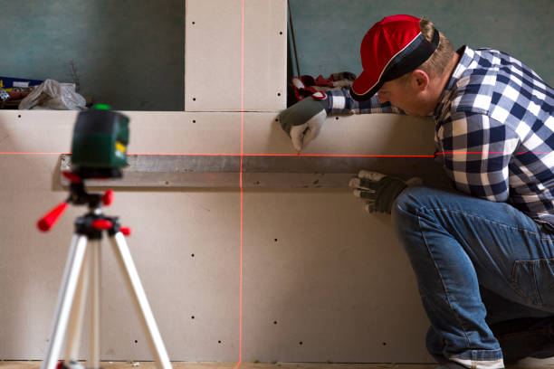 handyman auf trockene wand mit hilfe von laser-wasserwaage eine linie zeichnen - plastering station stock-fotos und bilder