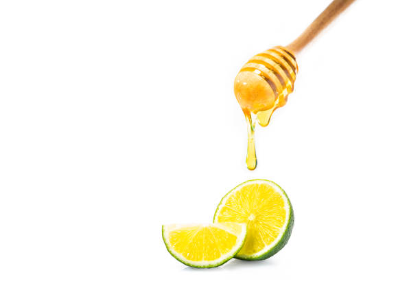 istock honey dipper with honey dripping down, and cut fresh lime on isolated white background, room for adding text or copy space 879176036