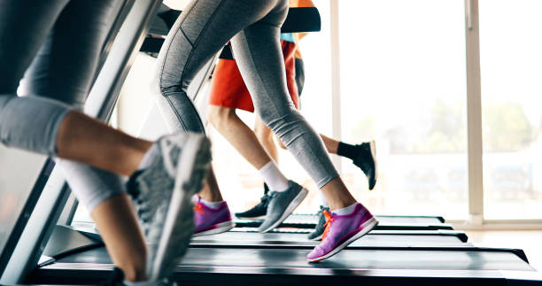 изображение людей, бегая на беговой дорожке в тренажерном зале - exercise equipment exercising dieting sport стоковые фото и изображения
