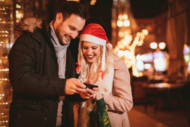 istock Young Couple Using Cell Phone In Christmas Night 879185878