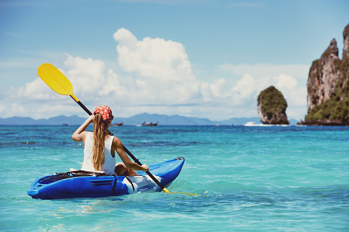 Girl on single kayak or canoe swims at tropical sea bay. Travel or kayaking concept