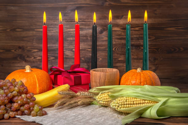 Kwanzaa festival concept with seven candles red, black and green, gift box, pumpkins, ears of wheat, grapes, corns, banana, bowl and fruits on wooden background, close up Kwanzaa festival concept with seven candles red, black and green, gift box, pumpkins, ears of wheat, grapes, corns, banana, bowl and fruits on wooden background, close up african american culture photos stock pictures, royalty-free photos & images