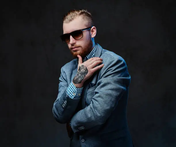 Photo of A man dressed in a suit and sunglasses.