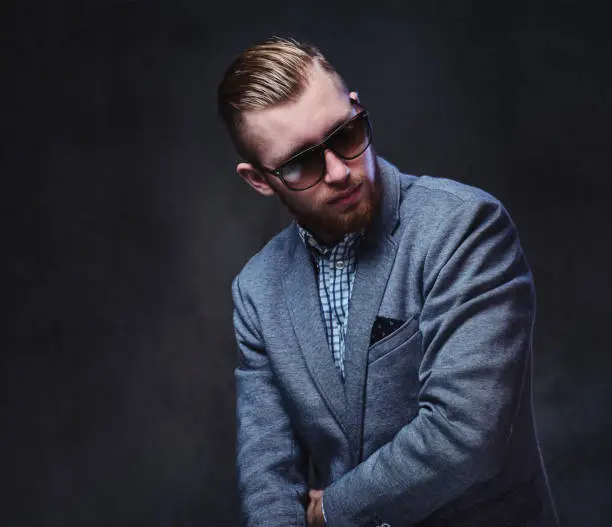 Photo of A man dressed in a suit and sunglasses.