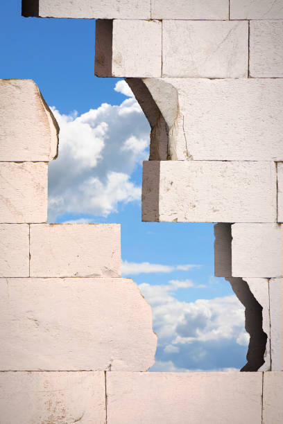 istock Through a cracked stone wall you see the sky - concept image 879254358