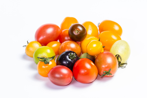 cluster of small cherry tomatoes in a variety of colors isolated on a white background