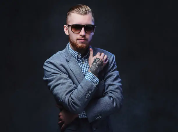 Photo of A man dressed in a suit and sunglasses.