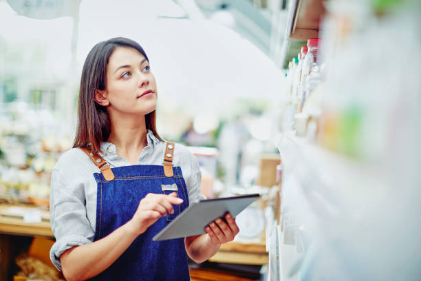istock Young deli owner holding digital tablet while standing in store 879257902