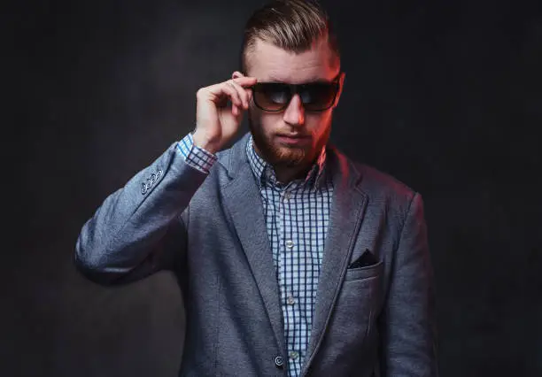 Photo of A man dressed in a suit and sunglasses.