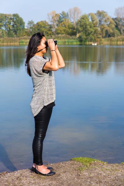 istock Woman looking through binoculars at water 879262120