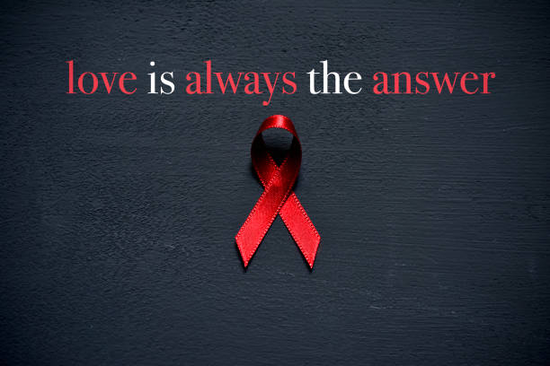 a red ribbon for the fight against AIDS and the text love is always the answer on a dark gray surface