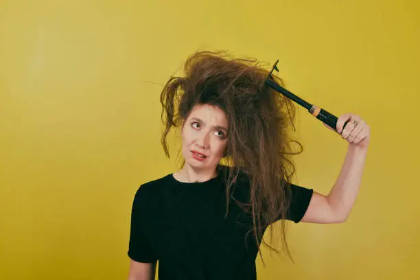 annoyed girl combs her hair with a rake