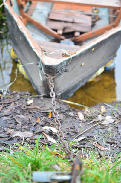 A dilapidated boat moored on the river bank by an iron chain