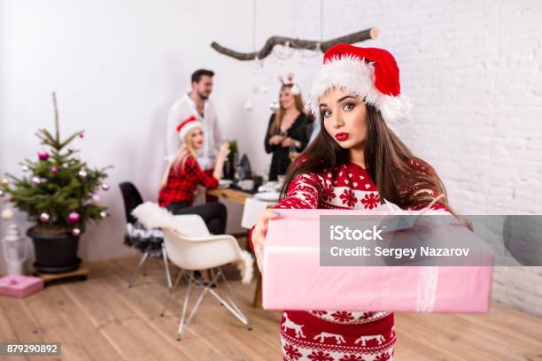 Portrait Of A Young Woman With A Pink Giftbox At Home On The Foreground Beautiful Brunette In A Santa Hat Red Costume With Deers Stock Photo - Download Image Now