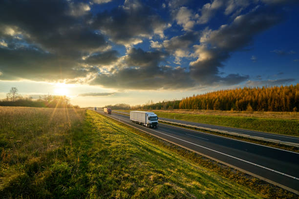 istock Trucks driving on the highway in autumn landscape at sunset with dramatic clouds 879293052