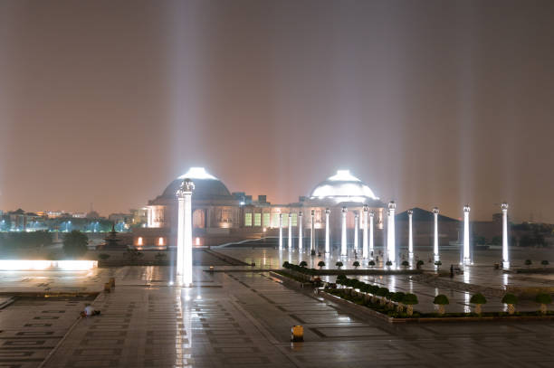 A city skyline is visible under a heavy rainstorm at night, with the bright lights of the city illuminating the dark sky. Rain falls in sheets, creating a dramatic and moody atmosphere.