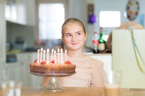 Lovely blonde girl have fun in front of a birthday cake with candles