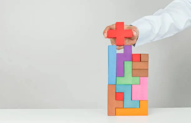 Putting the final building block onto the top of a rising pile signifying success and achievement.