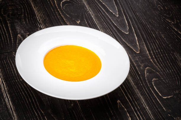 A bowl with pumpkin soup on a black wooden background. Top view. Copy space. Still life. Flat lay
