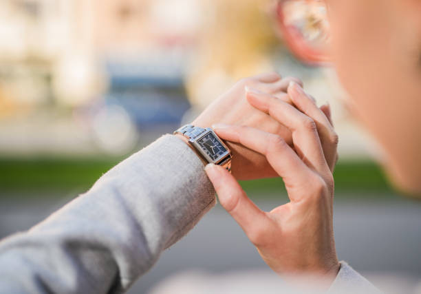 Young female dentist checking the time on her wristwatch white waiting for the patient in dental clinic