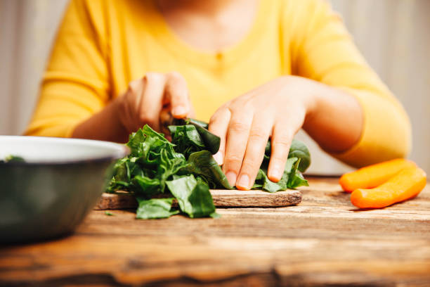 Young women at home cooking spinach stock photo