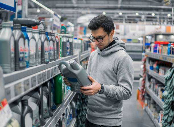 masculino cliente comprando motor óleo no supermercado carro de lubrificação - lubrificação - fotografias e filmes do acervo