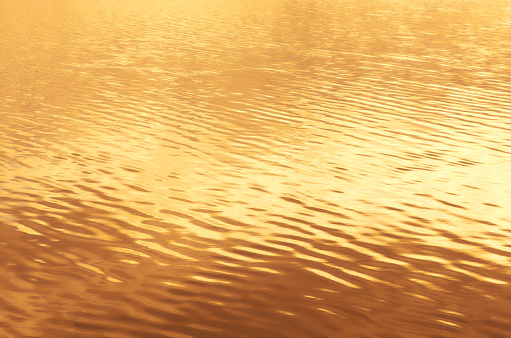 Gold sunset reflected in water ripple surface background