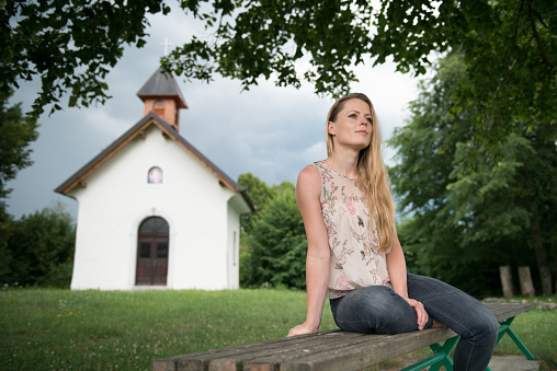 Beautiful Woman Sitting on Bench in Front of a Church