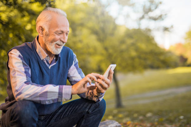 istock Happy senior man using his phone in the park. 879361894