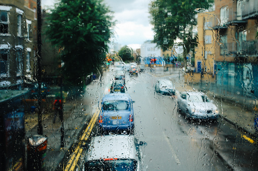 Traffic jam and people commuting on a rainy day in London downtown. Image taken from the city bus.
