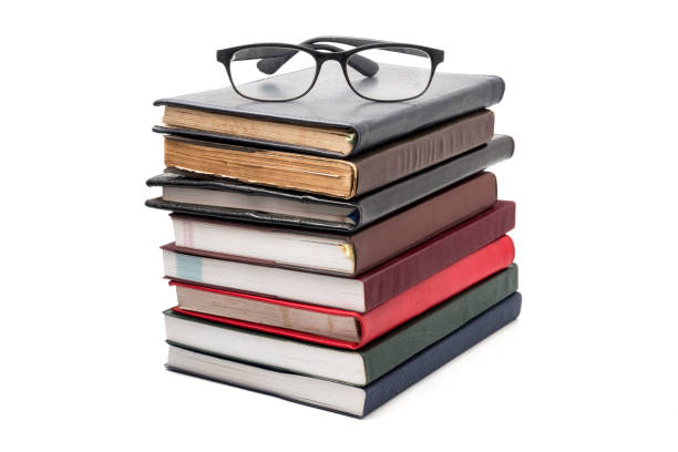 istock A stack of books with eyeglasses on a white background. 879481788
