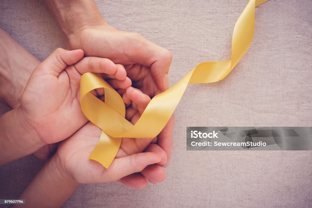 adult and child hands holding yellow gold ribbon, Sarcoma Awareness, Bone cancer, childhood cancer awareness Cancer - Illness Stock Photo