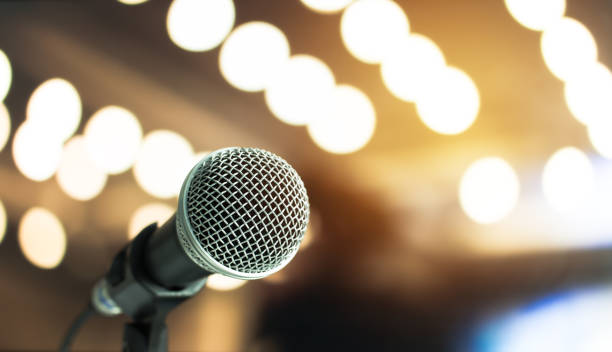 istock Microphone on abstract blurred of speech in seminar room or speaking conference hall light, Event concert bokeh background 879529808