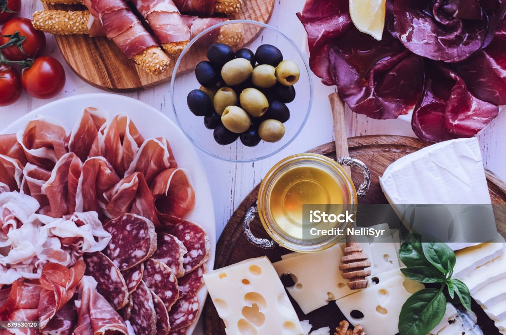 Table full of mediterranean appetizers Table full of mediterranean appetizers, tapas or antipasto. Assorted Italian food set. Delicious snack on party or picnic time. Chopping board with meat and cheese. Italian style banquet. Top view. Above Stock Photo